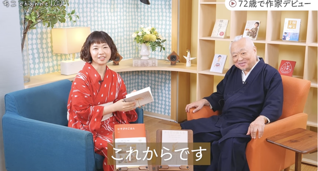 『からだの持ち主』と『むすびのごはん』を前に、ちこさんと笑顔で話すさえぐさ誠先生